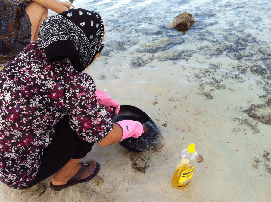 A refugee washes dishes in Nauru.