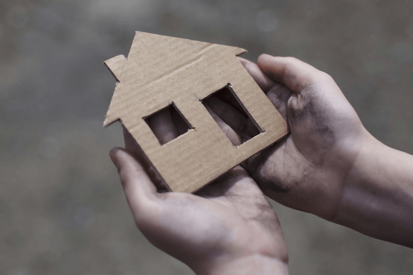 homeless boy holding a cardboard house, dirty hand