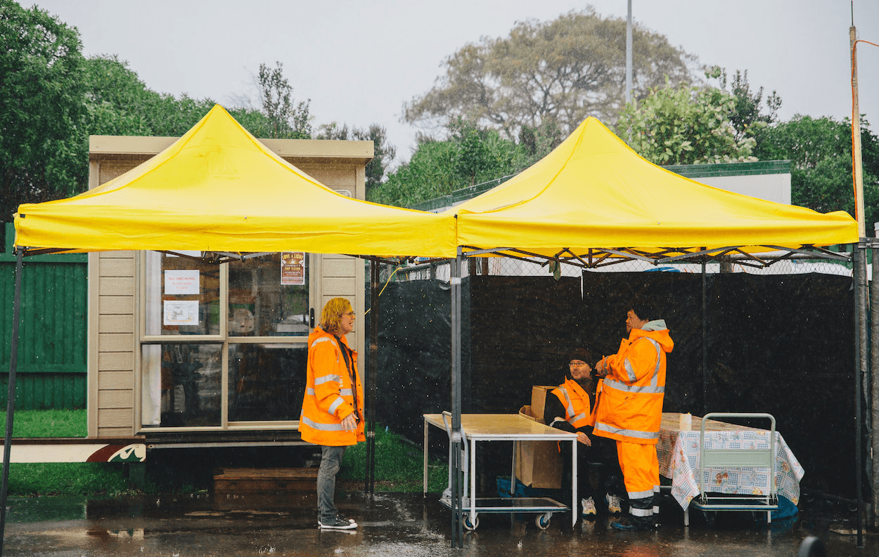 Taehuri (right) and volunteers wait for donations in the rain (Photo credit: Qiane Matata-Sipu)
