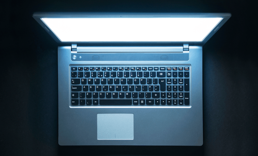 Laptop computer with screen glowing in the dark 
