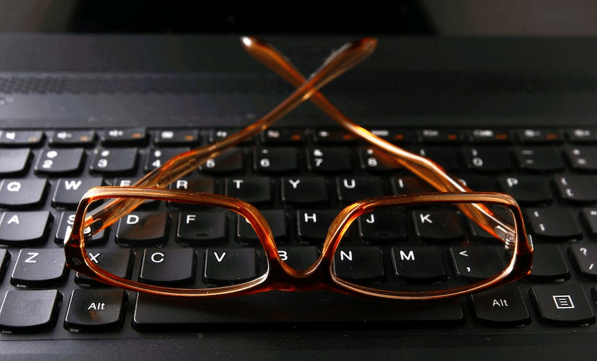 Photo of a pair of eyeglasses on a computer keyboard 
