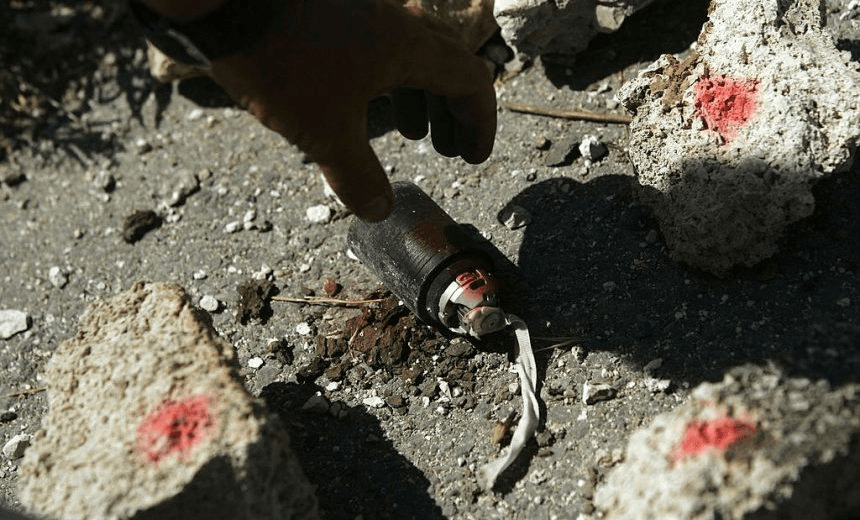 Mines Advisory Group employee Frederic Gras gingerly picks up an unexploded cluster bomb August 26, 2006 in Beit Yahoun, Lebanon. Cluster bombs, officially known as unexploded M42 submunitions, were used widely by the Israeli military in the recent conflict in Lebanon and often leave unexploded remnants that can explode when handled weeks or months later by civilians.  (Photo by Chris Hondros/Getty Images) 
