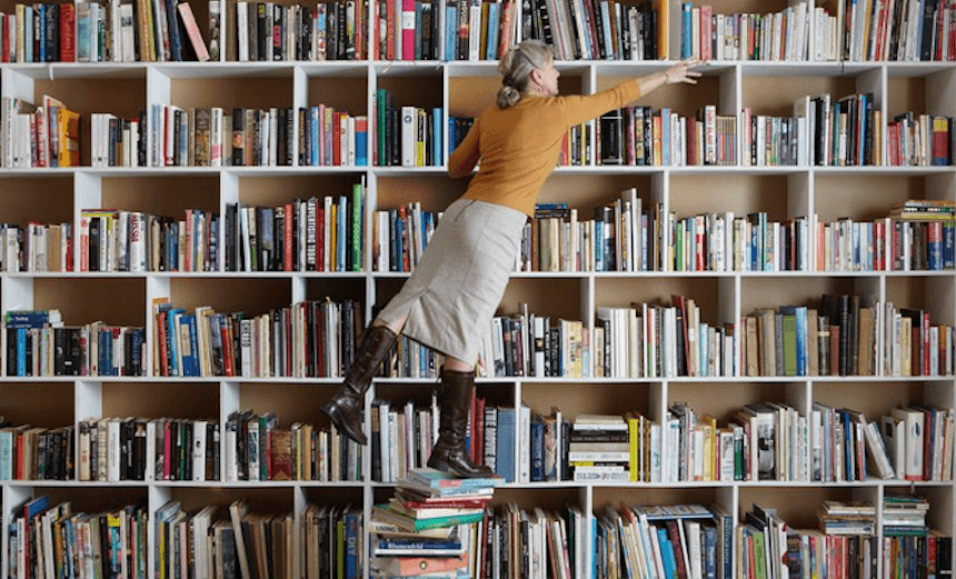 Older woman standing on stack of books