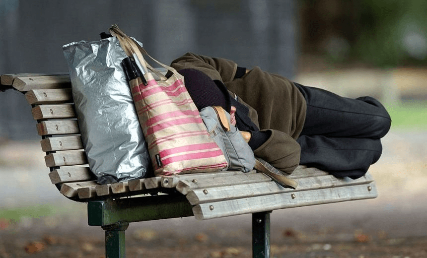 A homeless person sleeping on a park bench at Victoria Park, Auckland. (Photo by Dean Purcell/Getty Images)