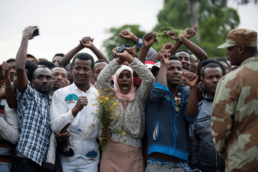 Residents of Bishoftu crossed their wrists above their heads as a symbol for the Oromo anti-government protesting movement during the Oromo new year holiday Irreechaa in Bishoftu on October 2, 2016. Several people were killed in a stampede near the Ethiopian capital on October 2 after police fired tear gas at protesters during a religious festival, according to an AFP photographer at the scene. Several thousand people had gathered at a sacred lake to take part in the Irreecha ceremony, in which the Oromo community marks the end of the rainy season, where participants crossed their wrists above their heads, a gesture that has become a symbol of Oromo anti-government protests. The event quickly degenerated, with protesters throwing stones and bottles and security forces responding with baton charges and then tear gas grenades. / AFP / Zacharias ABUBEKER (Photo credit should read ZACHARIAS ABUBEKER/AFP/Getty Images)