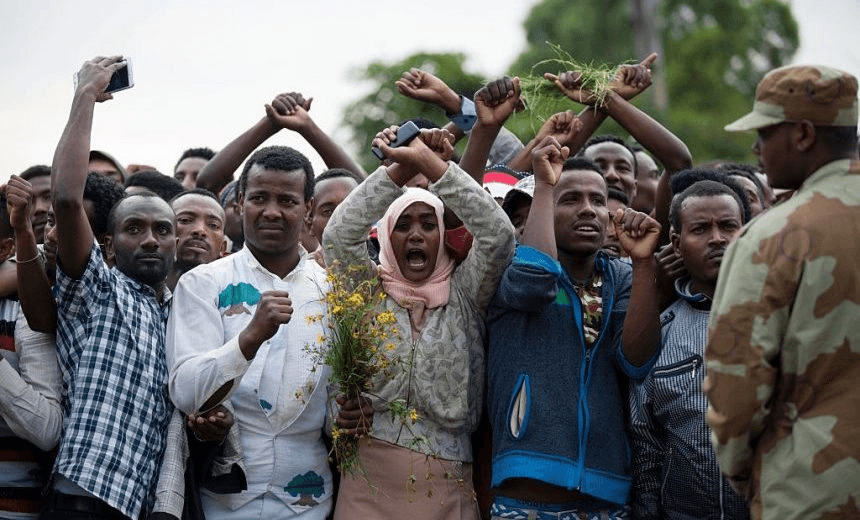 Residents of Bishoftu crossed their wrists above their heads as a symbol for the Oromo anti-government protesting movement during the Oromo new year holiday Irreechaa in Bishoftu on October 2, 2016.
Several people were killed in a stampede near the Ethiopian capital on October 2 after police fired tear gas at protesters during a religious festival, according to an AFP photographer at the scene. Several thousand people had gathered at a sacred lake to take part in the Irreecha ceremony, in which the Oromo community marks the end of the rainy season, where participants crossed their wrists above their heads, a gesture that has become a symbol of Oromo anti-government protests. The event quickly degenerated, with protesters throwing stones and bottles and security forces responding with baton charges and then tear gas grenades. / AFP / Zacharias ABUBEKER (Photo credit should read ZACHARIAS ABUBEKER/AFP/Getty Images)
