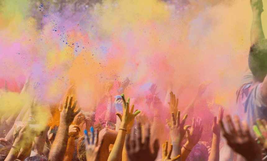 People enjoying the colorful Holi festival in Barcelona a indian tradition to welcome the spring covering himself of gulal powder, moment when all the crowd throwing the colorful powder to the air with arms raised. Catalonia, Europe. 

