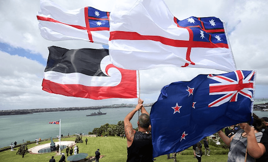 Members of the public hold flags as Navy ships sail into the Waitemata Harbour as part of the fleet entry to celebrate the Royal New Zealand Navy’s 75th Birthday in Auckland on November 16, 2016. Photo:  MICHAEL BRADLEY/AFP/Getty Images) 
