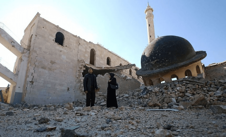 Kefa Jawish (R) and her husband Tajeddin Ahmed walk among the ruins of a destroyed mosque in Aleppo’s Hanano district as they head to check their house for the first time in four years in the city’s northeastern Haydariya neighbourhood on December 4, 2016.   
 Jawish was among hundreds of Syrians returning to east Aleppo in recent days after the army recaptured large swathes of the city from rebels and encouraged residents to visit neighbourhoods and homes they left years earlier. 
  / AFP / Youssef KARWASHAN / TO GO WITH AFP STORY BY RIM HADDAD        (Photo credit should read YOUSSEF KARWASHAN/AFP/Getty Images) 
