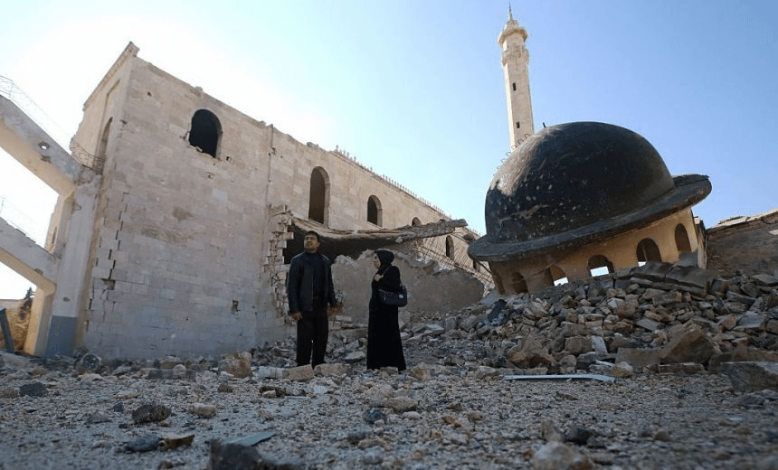 Kefa Jawish (R) and her husband Tajeddin Ahmed walk among the ruins of a destroyed mosque in Aleppo's Hanano district as they head to check their house for the first time in four years in the city's northeastern Haydariya neighbourhood on December 4, 2016. Jawish was among hundreds of Syrians returning to east Aleppo in recent days after the army recaptured large swathes of the city from rebels and encouraged residents to visit neighbourhoods and homes they left years earlier. / AFP / Youssef KARWASHAN / TO GO WITH AFP STORY BY RIM HADDAD (Photo credit should read YOUSSEF KARWASHAN/AFP/Getty Images)
