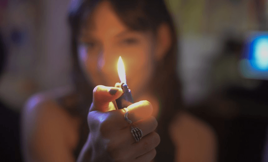 Close-Up Of Woman Igniting Cigarette Lighter At Home