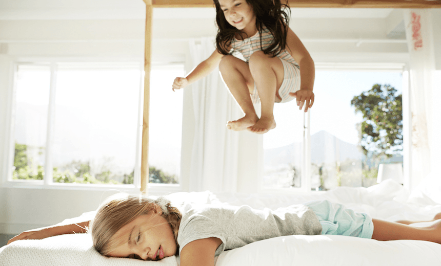 Girl sleeping while sister jumping in bed