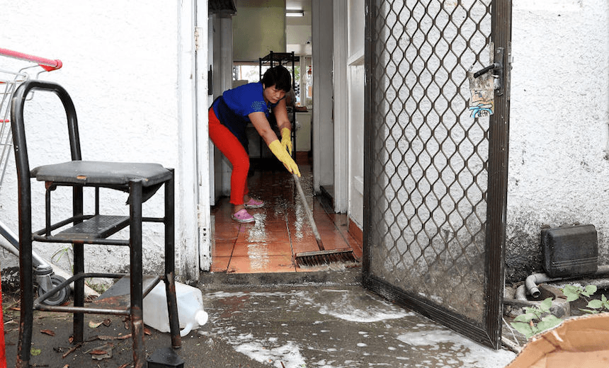 Hui Qui cleans up her takeaway shop after flash flooding in Great North Rd, New Lynn on March 13, 2017 in Auckland. (Photo by Fiona Goodall/Getty Images) 
