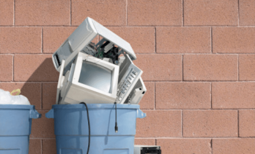 Trash can filled with computer tower, monitor and keyboard