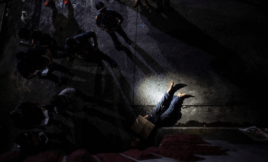 TOPSHOT – EDITORS NOTE: Graphic content / In this picture taken on July 8, 2016, police officers investigate the dead body of an alleged drug dealer, his face covered with packing tape and a placard reading “I’m a pusher”, on a street in Manila. 
Philippine President Rodrigo Duterte on July 1 urged communist rebels to start killing drug traffickers, adding another layer to a controversial war on crime in which he has warned thousands will die. / AFP / NOEL CELIS        (Photo credit should read NOEL CELIS/AFP/Getty Images) 
