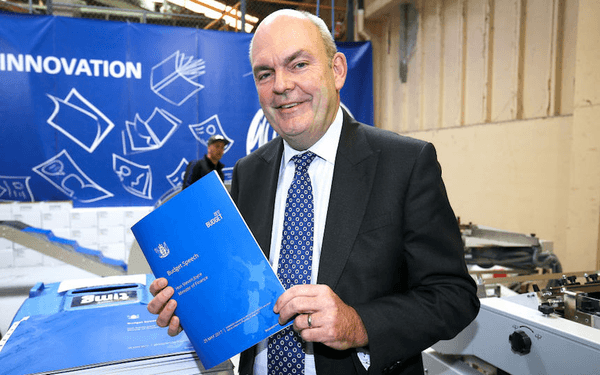 Finance Minister Steven Joyce poses with the Budget described as a the ‘one dollar bill’ budget by almost nobody (Photo by Hagen Hopkins/Getty Images) 
