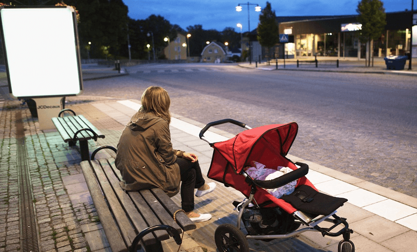 Woman waiting on a bench with a baby carriage, Sweden.