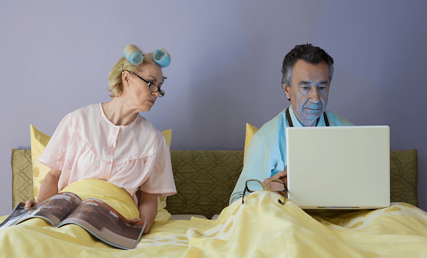 Couple in bed with laptop and magazine
