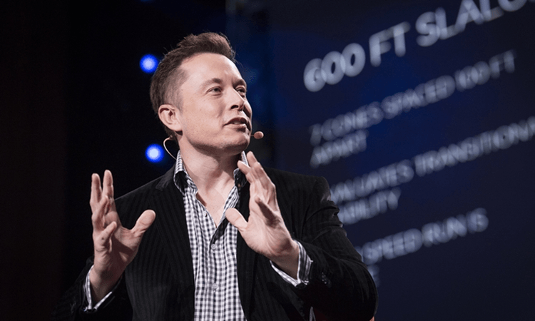 white man with weird hair and a half open mouth (it's elon musk) has a blurry screen in the background.