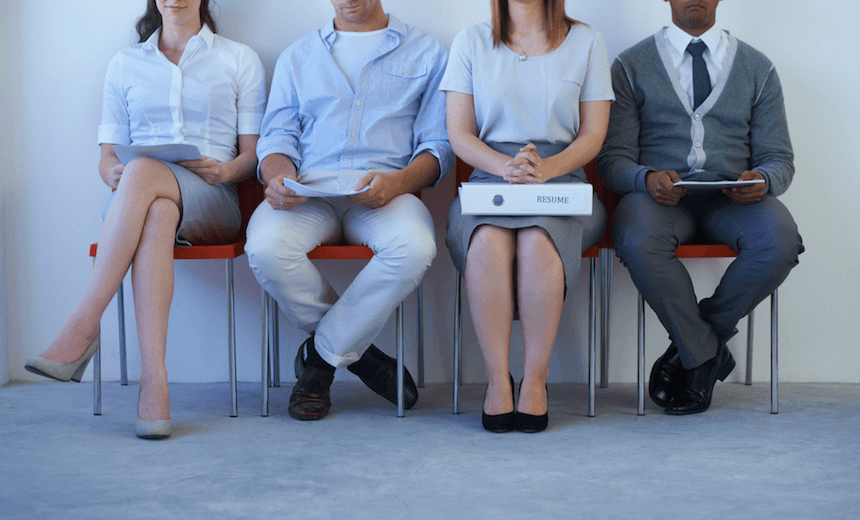 A young woman with a large resume sitting with other prospective employees