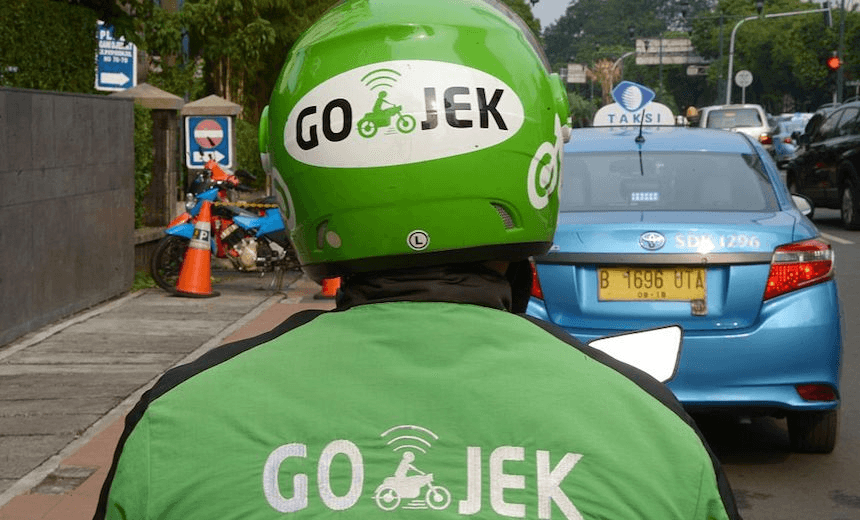 TO GO WITH Indonesia-transport-traffic-Internet,FOCUS by Nick Perry 
This picture taken on June 11, 2015 shows a motorcycle driver with Indonesian start-up Go-Jek waiting for customers along a street in Jakarta.  A popular motorbike-hailing app by Go-Jek is putting a new, two-wheeled spin on smartphone taxi services in the Indonesian capital, with thousands of motorcyclists in distinctive green jackets and helmets offering commuters an escape from Jakarta’s notorious traffic gridlock.      AFP PHOTO / ADEK BERRY        (Photo credit should read ADEK BERRY/AFP/Getty Images) 
