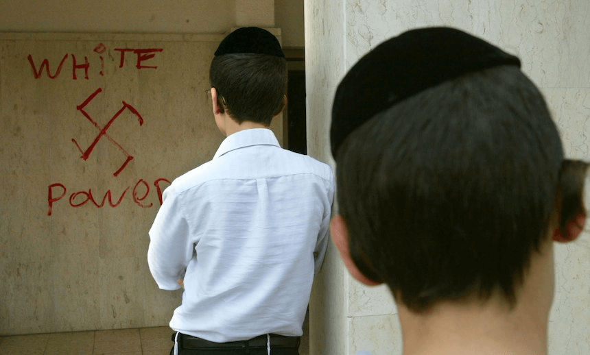 Jewish boys look at anti-semitic graffiti which was sprayed on the walls of a synagogue March 5, 2006 in Petah Tikva in central Israel. (Photo by Uriel Sinai/Getty Images) 
