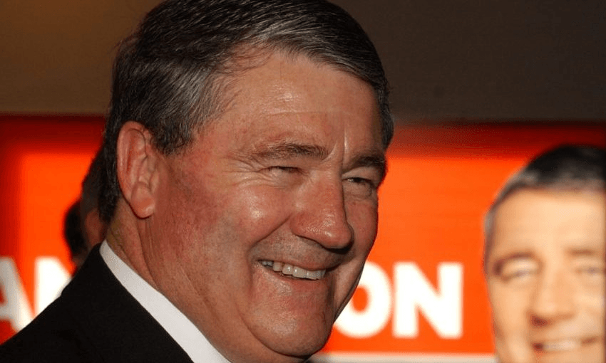 a smiling white man brightly lit with slicked back salt and pepper here