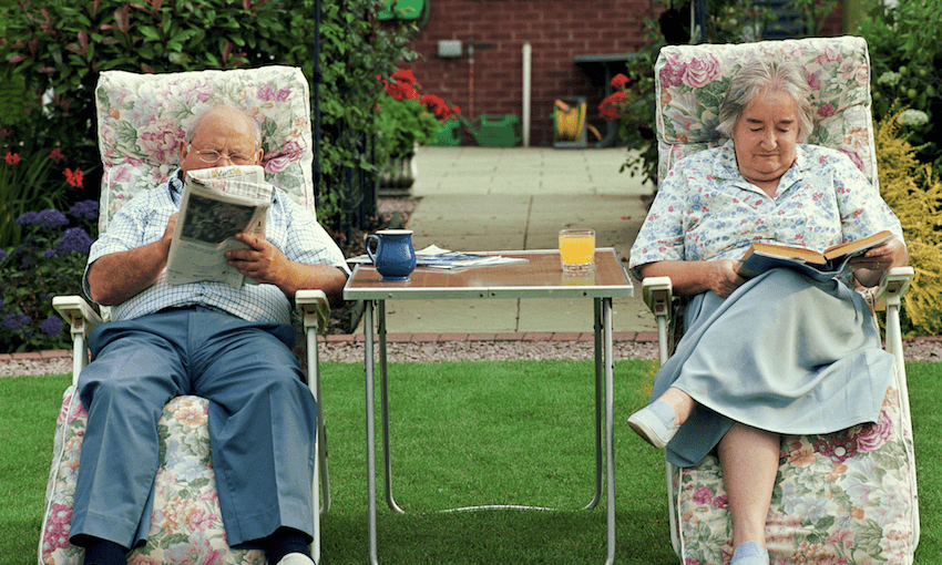 Senior couple reading on adjacent garden chairs