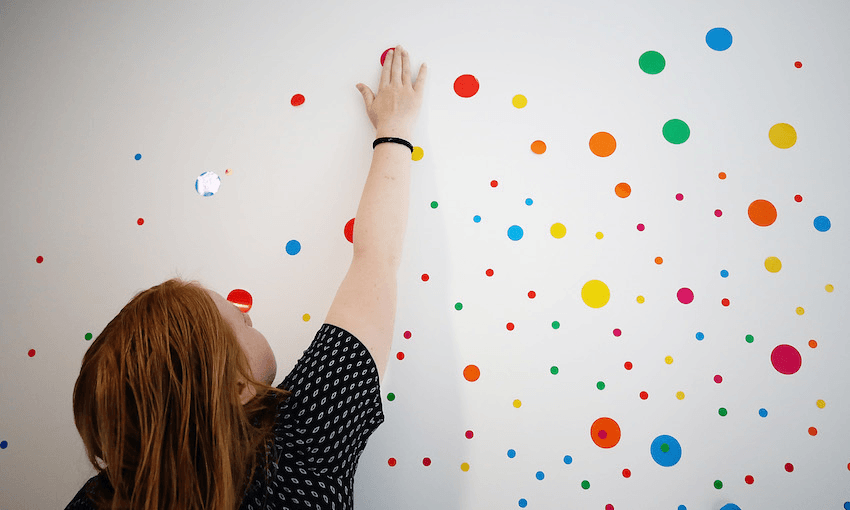 Visitors make their mark on Yayoi Kusama’s ‘The obliteration room’ at Auckland Art Gallery (Photo by Hannah Peters/Getty Images). 
