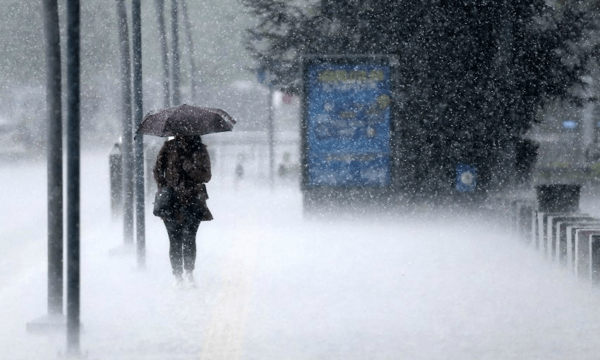 A woman walks away from a bus stop during heavy rain (Getty Images)  
