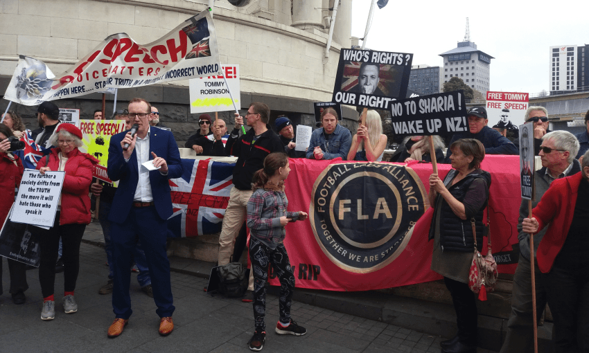 Act Party candidate Stephen Berry, speaking at the Free Speech protest. Behind him is a banner for the UK based Football Lads Alliance, a self-proclaimed anti-extremist group that has been linked to the UK far right. (Photo: Alex Braae)  
