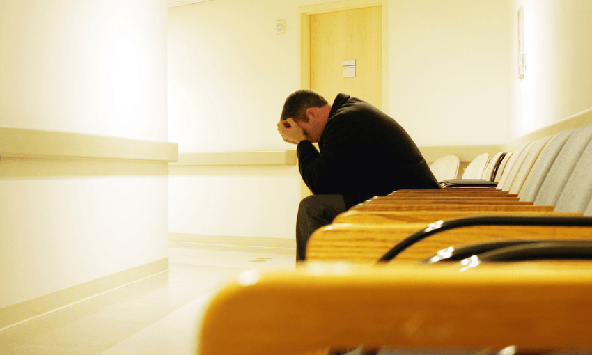 man sitting in waiting room with head in hands