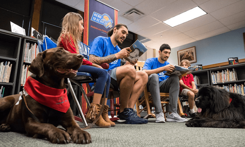 Steven Adams reads with Enes Kanter and children and dogs (Photo by Zach Beeker/OKC Thunder) 
