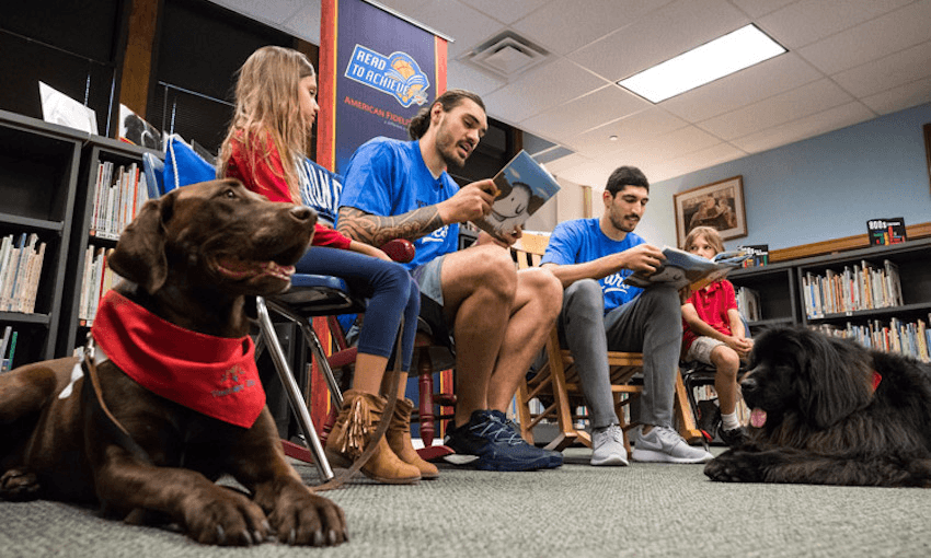 Steven Adams reads with Enes Kanter and children and dogs (Photo by Zach Beeker/OKC Thunder)