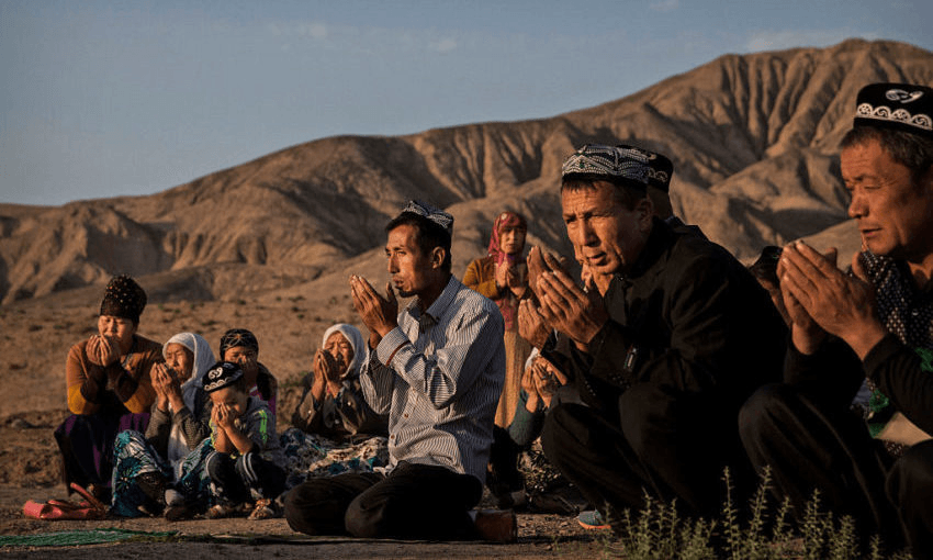 A Uighur family pray at the grave of a loved one in Turpan County, Xinjiang. (Photo: Kevin Frayer/Getty Images 
