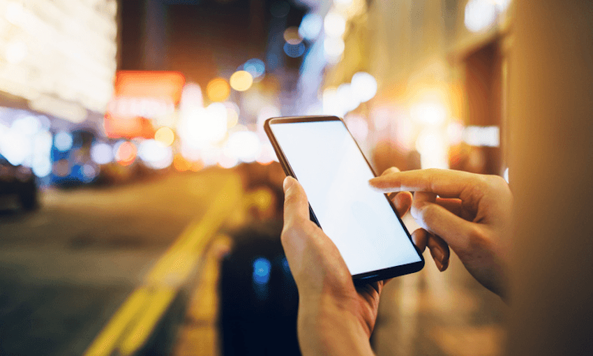 Woman requesting a ride with smartphone in downtown city street at night 
