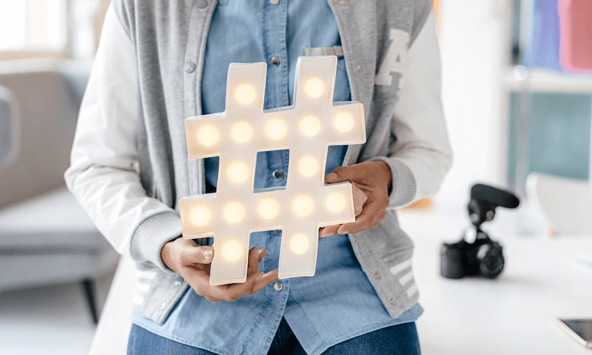 Young woman holding hashtag sign in studio