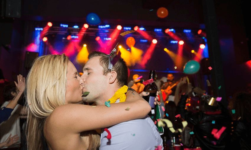 Confetti falling kissing couple enjoying New Year celebration