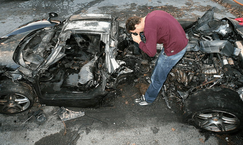 Nice, FRANCE:  A journalist films the wreck of a black Ferrari driven by a member of the Russian parliament, Suleyman Kerimov after the car hit a tree and burst into flames (VALERY HACHE/AFP/Getty Images) 
