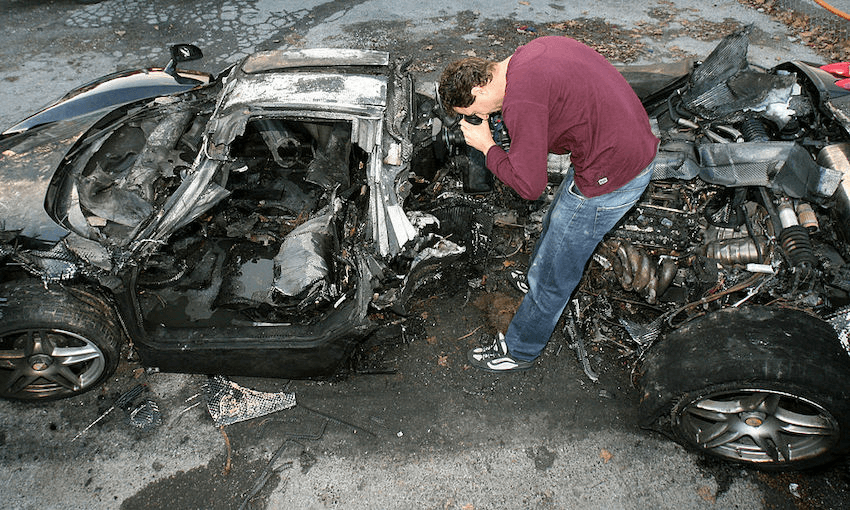 Nice, FRANCE: A journalist films the wreck of a black Ferrari driven by a member of the Russian parliament, Suleyman Kerimov after the car hit a tree and burst into flames (VALERY HACHE/AFP/Getty Images)