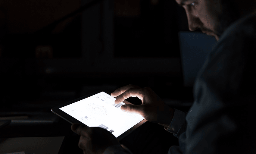 Businessman working on tablet in the dark, close-up