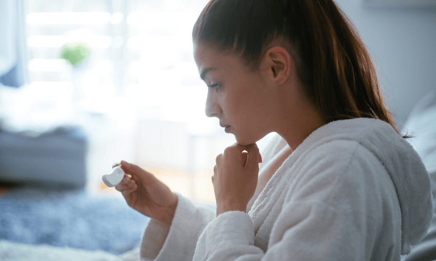 A worried woman checks a pregnancy test. Photo: Getty Images. 
