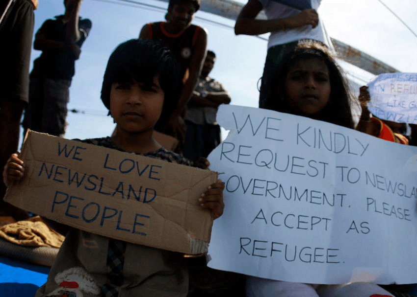 Sri Lankan asylum seekers hold signs and plead for assistance as they seek asylum to New Zealand onboard the MV Alicia, after refusing to leave their boat for four days on July 13, 2011 in Bintan, Sumatra, Indonesia. (Photo by Yuli Seperi/Getty Images) 
