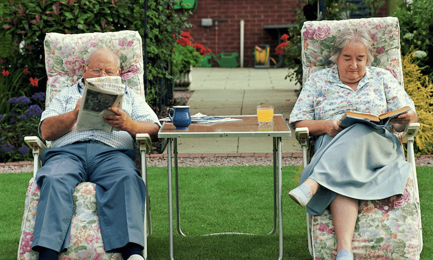 Wonderful old couple reading on lawn chais, a wee table in between them, on a lawn