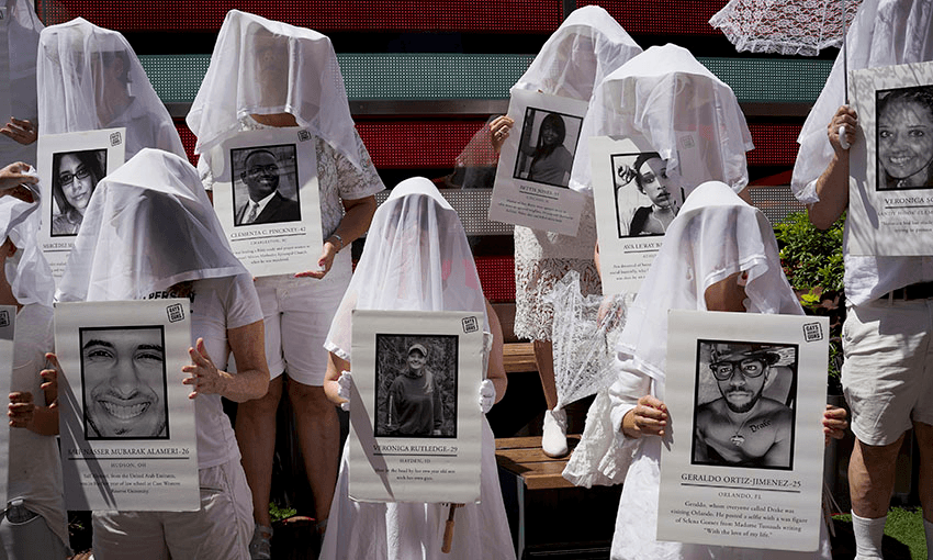 Protesters against gun violence dressed in white hold up photos of the victims of gun violence in Times Square in response to recent mass shootings in El Paso, Texas and Denton, Ohio. (Photo by Go Nakamura/Getty Images) 
