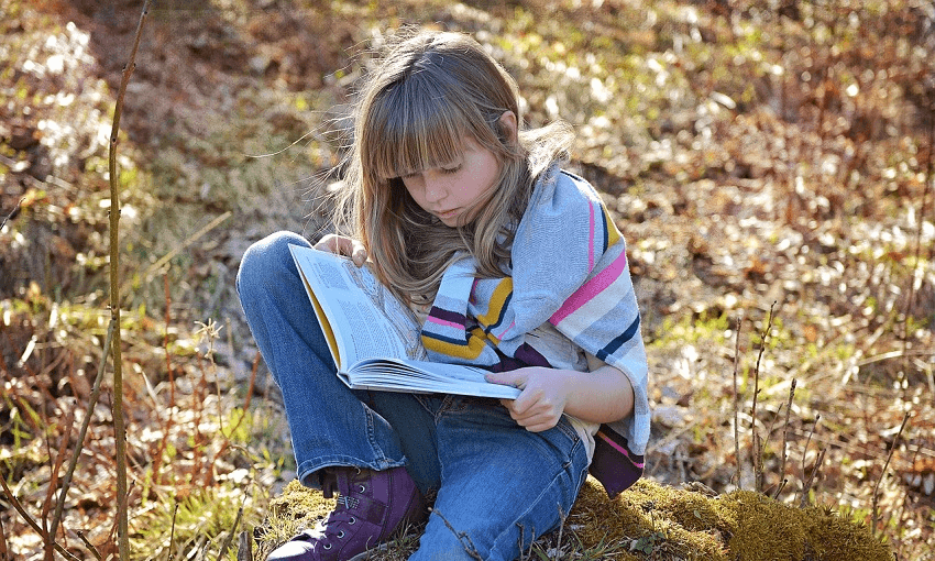 Young girl / Child reading a book outside 
