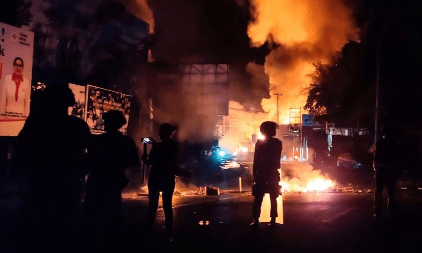 Security forces watch as a building burns after hundreds of demonstrators marched near Papua’s biggest city Jayapura on August 29. pHOTO: INDRA THAMRIN HATTA/AFP/Getty Images