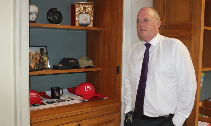 National’s leader Todd Muller, next to an office shelf filled with American political paraphernalia, including a hat that turned into a story of its own after he became party leader (Photo: Alex Braae)  

