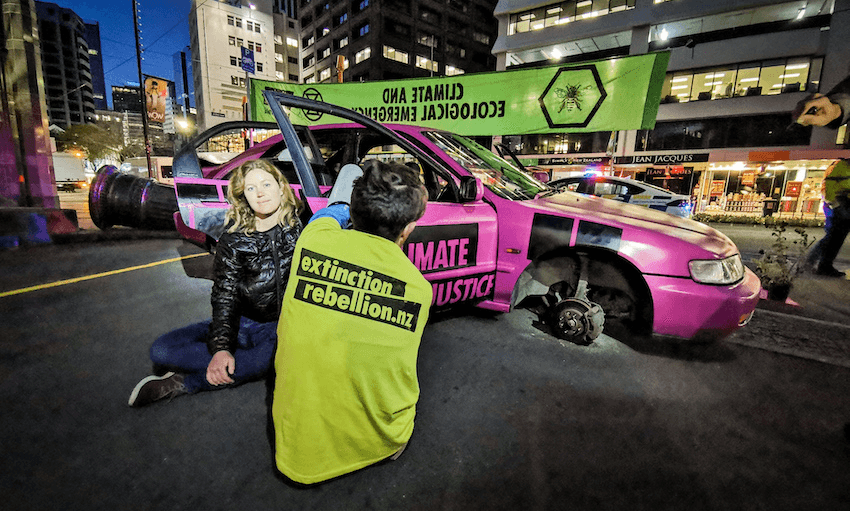 Extinction Rebellion’s Melanie Vautier chained herself to a car as part of today’s protest in central Wellington (supplied)  
