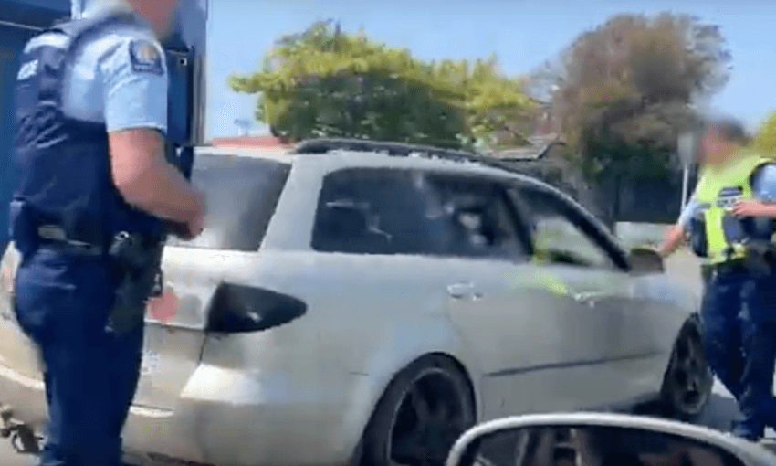 An armed police officer making an arrest in Hamilton (Image via youtube/Radio NZ) 

